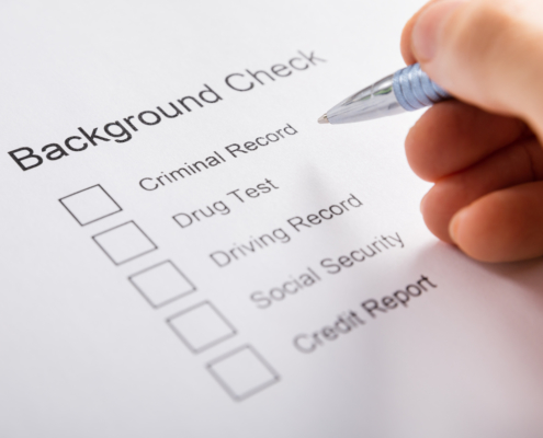 Close-up Of Person Hand Filling Background Check Provider Form